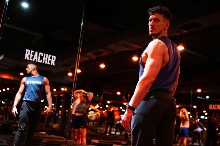 Barry’s Bootcamp trainer facing floor-to-ceiling mirror. The word Reacher is printed on the mirror