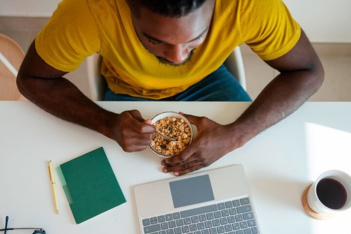 Man sitting in front of a laptop eating cereal