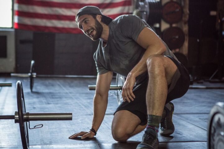 Man kneeling next to dumbbell, resting