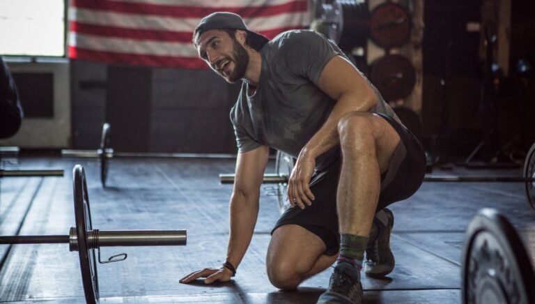 Man kneeling next to dumbbell, resting